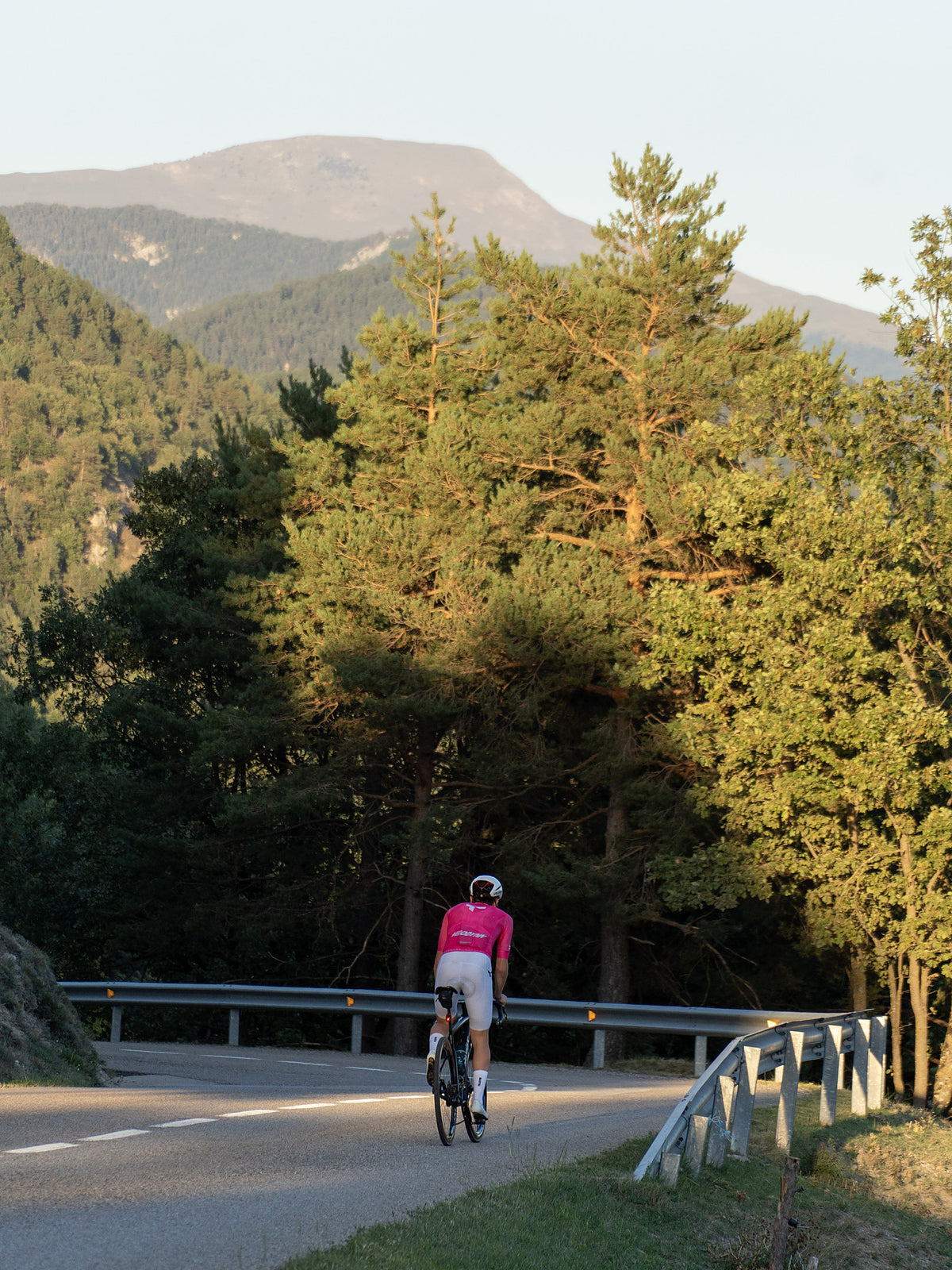 Ciclista con el maillot Ráfaga en una carretera entre pinos