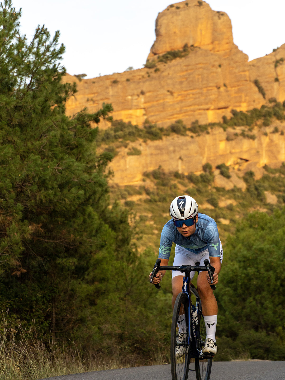 Ciclista con el maillot Grafito bajo un acantilado de arenisca